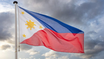 Philippines sign symbol. Republic of the Philippines national flag on a pole waving against cloudy sky background.